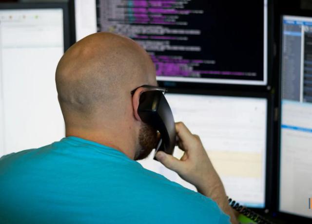 Support technician taking a call at a multi-monitor workstation